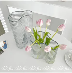 Transparent ribbed glass vase detail with fresh pink tulips, elegant minimalist home decor.