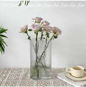 Transparent ribbed glass vase with elegant roses, perfect for modern home decor and table styling.