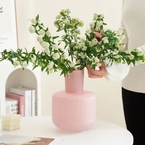 Rosa mattierte Glasvase mit weißem Blumenarrangement für moderne minimalistische Heimdekoration.
