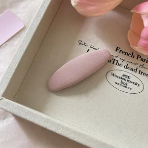 Close-up van een schattige roze stoffen haarspeld in een beige tray met tulpen.
