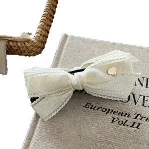 Korean style white fabric bow hair clip with cute gold heart charm, elegant and chic hair accessory.