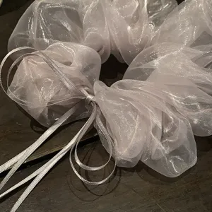 Close-up detail van mistpaarse organza haarscrunchie met linten en delicate textuur.