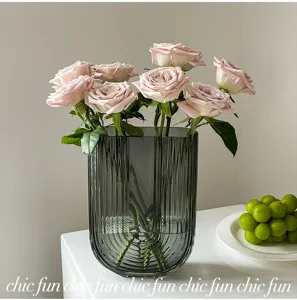 Vue détaillée du vase en verre nordique à rayures verticales et roses dans un salon confortable.