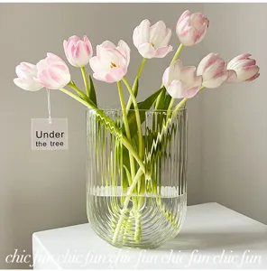 Vase en verre transparent avec des rainures verticales et de superbes tulipes roses.