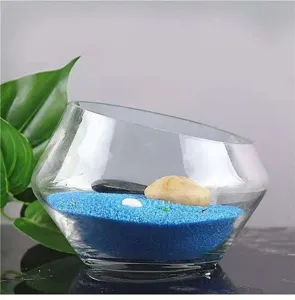 Transparentes schräges Glasvasen-Detail mit blauem Dekosand und Steinen für die schöne Hydrokultur.