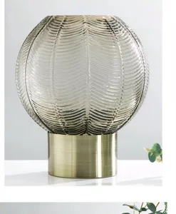 Close-up of ribbed glass vase with elegant metallic base, modern Nordic interior decoration detail.