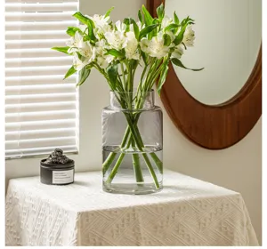 Nahaufnahme einer klaren Glasvase mit weitem Mund in einer Inneneinrichtung mit frischen Blumen.