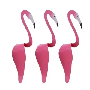 Three pink metal flamingo garden ornaments arranged side by side.