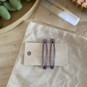Detailaufnahme von lila transparenten tropfenförmigen Haarklammern auf Karte chic.