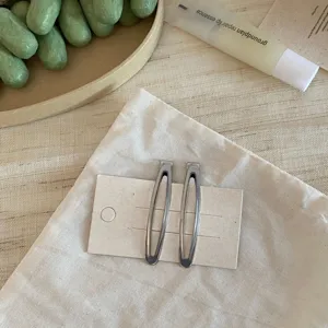 Detailansicht einfacher silberner Tropfen-Metall-Haarspangen auf Trägerkarte und Beutel.