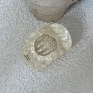 Elegante ivoren hars ovale haarspeld met subtiele marmertextuur voor chique haarstijlen.