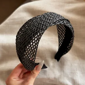 Détail de serre-tête large tissé noir, design en maille élégant accessoire cheveux femme.