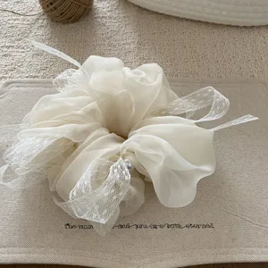 Λεπτομερές κοντινό πλάνο λευκού scrunchie οργάντζας μαλλιών με λεπτή δαντέλα και πέρλα.