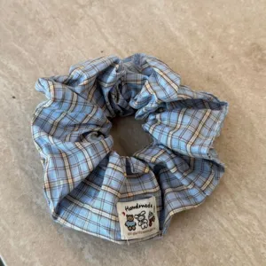 Nahaufnahme des blauen karierten Stoff-Haargummis, handgefertigter elastischer Pferdeschwanz.