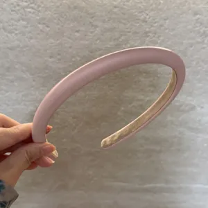 Vue détaillée du serre-tête rembourré en cuir rose, montrant sa texture douce et sa forme haute.