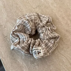 Nahaufnahme eines süßen braunen Karo-Stoff-Haargummis, weiches flauschiges Mode-Accessoire.