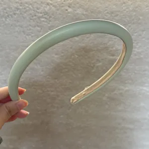 Vue détaillée du serre-tête rembourré en cuir vert menthe, montrant son volume et sa texture douce.