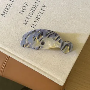 Jolie pince à cheveux en acétate lamantin, motif gris détaillé et design doré chic.