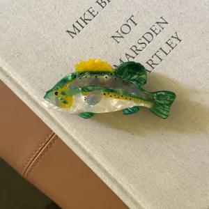 Gros plan sur une pince à cheveux en acétate en forme de poisson vert et jaune unique.