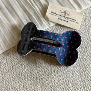 Primo piano dettagliato di una graziosa molletta per capelli a osso blu con pois rosa.