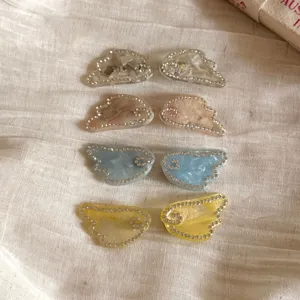 Detail view of rhinestone angel wing hair clips in assorted colors, elegant side hair accessories.