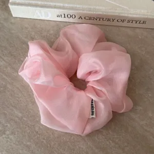 Rosa Organza Haargummi Detailaufnahme mit weicher Netzstruktur und filzigem Label.