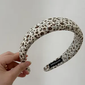 Close-up detail of vintage floral fabric headband, showing fine texture and inner handmade label.