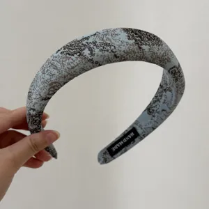 Detailed view of vintage blue fabric padded headband with abstract pattern, handmade craft.