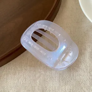 Detail view of pearlescent jelly hair claw clip, showing transparent oval design and spring.