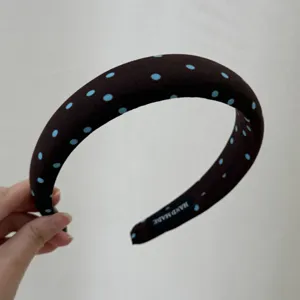 Closeup of a chic dark brown headband featuring cute blue polka dots and a handmade label.