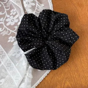Black polka dot hair scrunchie detail shot, elegant fabric hair accessory with cute white dots design.