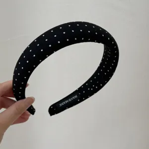 Detail view of black polka dot fabric headband, elegant hair hoop accessory for women.