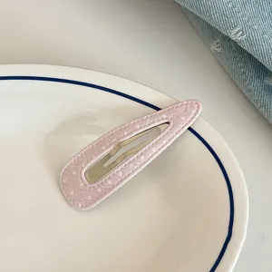 Close-up of a sweet pink polka dot snap hair clip on a white ceramic plate, detail.