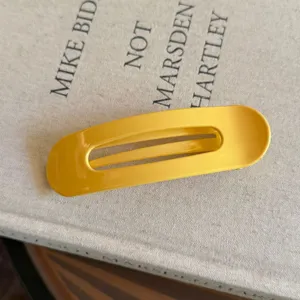 Vue détaillée de la pince à cheveux ovale jaune vif avec finition brillante quotidienne.