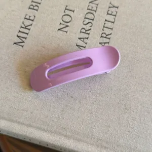 Détail en gros plan d'une pince à cheveux ovale violette brillante avec un design évidé.