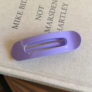 Détail de pince à cheveux ovale violette avec une surface brillante effet bonbon.