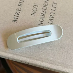 Gros plan d'une pince à cheveux ovale blanche minimaliste, mettant en valeur sa texture lisse.