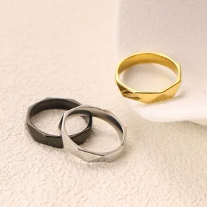 Detail shot of multi-faceted geometric titanium steel rings in gold, silver, and black finishes.