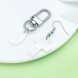 Nahaufnahme von DIY Schmuckzubehör, weiße Muschel Kreuz und Tropfen Anhänger Details.