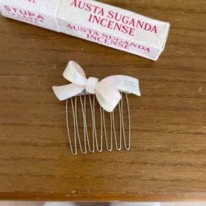 Detail view of the elegant white pearlescent bow hair comb with metal teeth for women styling.