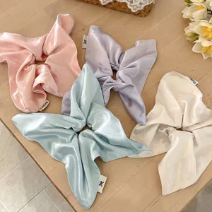Detail view of pastel satin ribbon hair scrunchies, elegant bow design for styling.