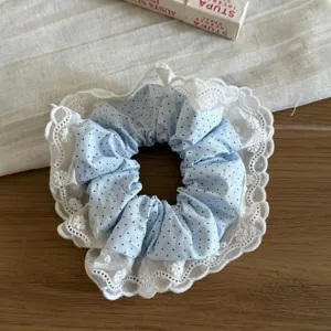 Primer plano del coletero de lunares azul claro con delicado borde de encaje blanco.