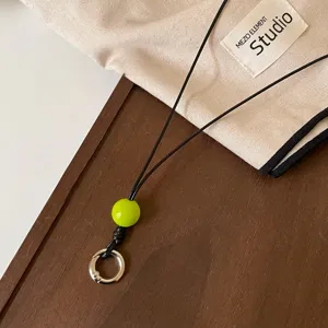 Vista de detalle de cordón de gafas de cuero negro con cuenta verde y anillo.