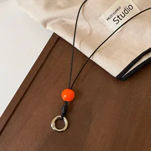 Cordón de gafas negro estilo coreano elegante con cuenta naranja y anillo de metal.