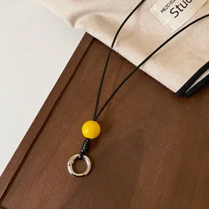 Vista detallada de correa para gafas de cuero negro con cuenta amarilla y anillo metálico.