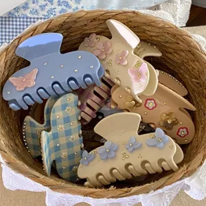 Vue détail de pinces à cheveux en acétate assorties avec strass et papillons dans un panier.