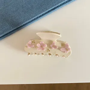 Vue détaillée d'une élégante pince à cheveux en acétate avec des fleurs roses et strass.