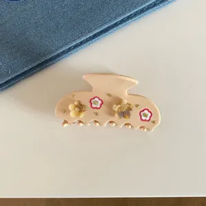 Vue rapprochée de la pince à cheveux en acétate rose ornée de fleurs en strass scintillantes.
