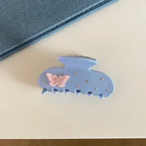 Détail d'une pince à cheveux bleue avec papillon rose et strass pour coiffure