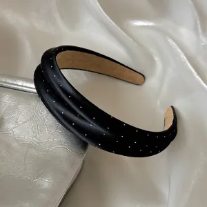 Vista detallada de la elegante diadema ancha de satén negro con encantadores lunares blancos.